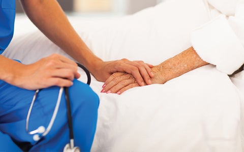 nurse-and-woman-holding-hand-in-bed