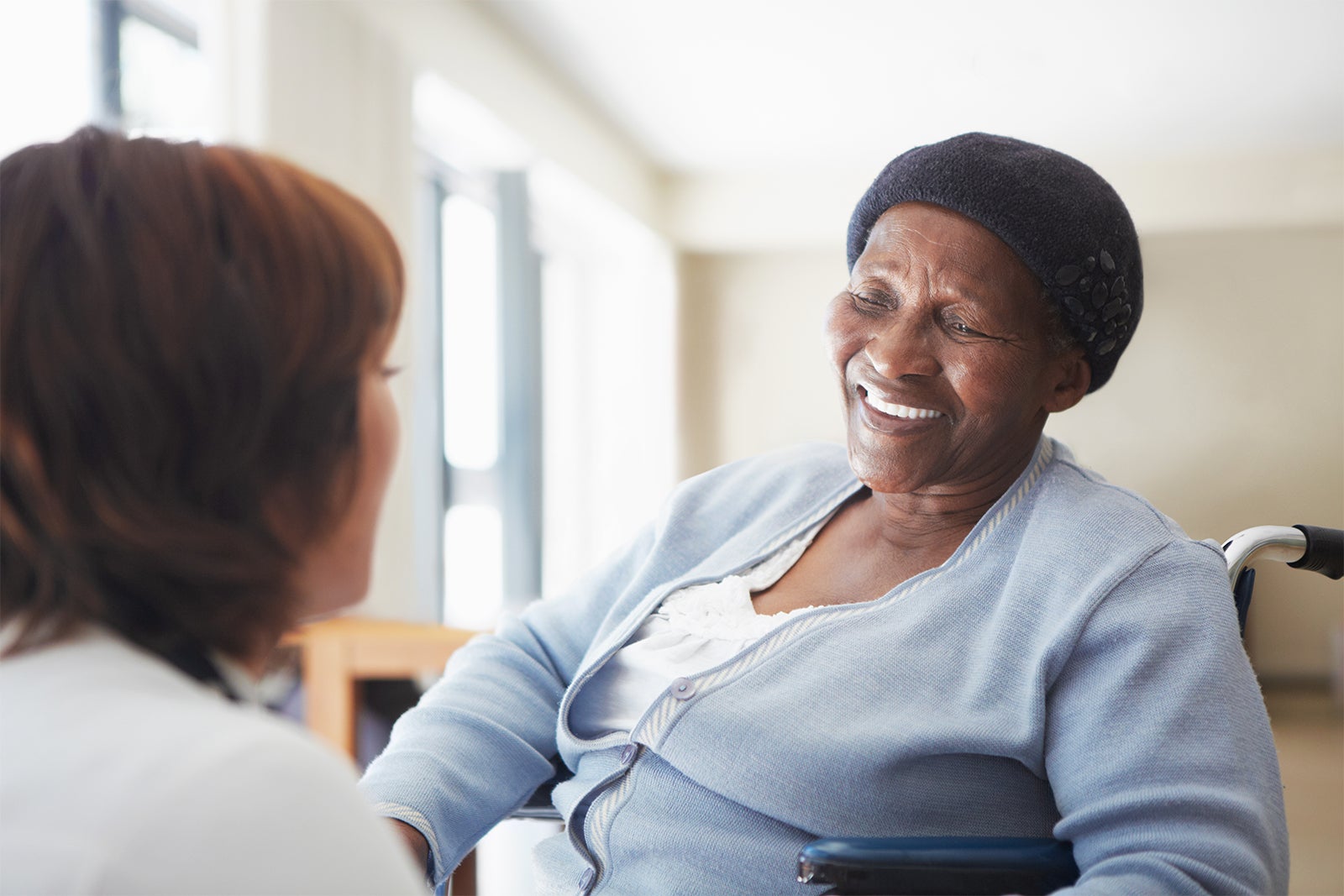 Patient compliance: Start the conversation Nurse speaking with elderly female patient in wheelchair.