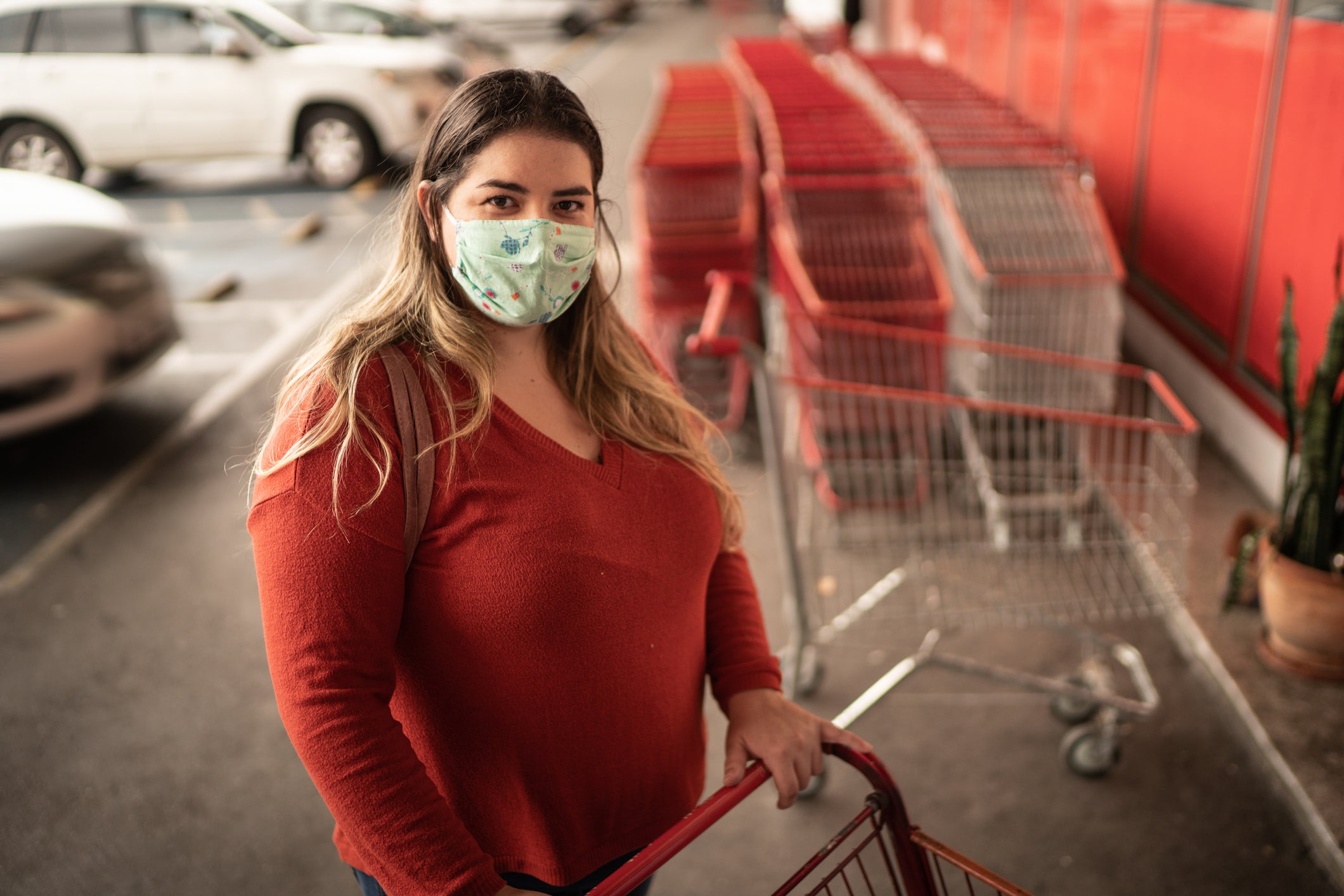 Portrait of woman wearing face mask picking shopping cart in supermarket