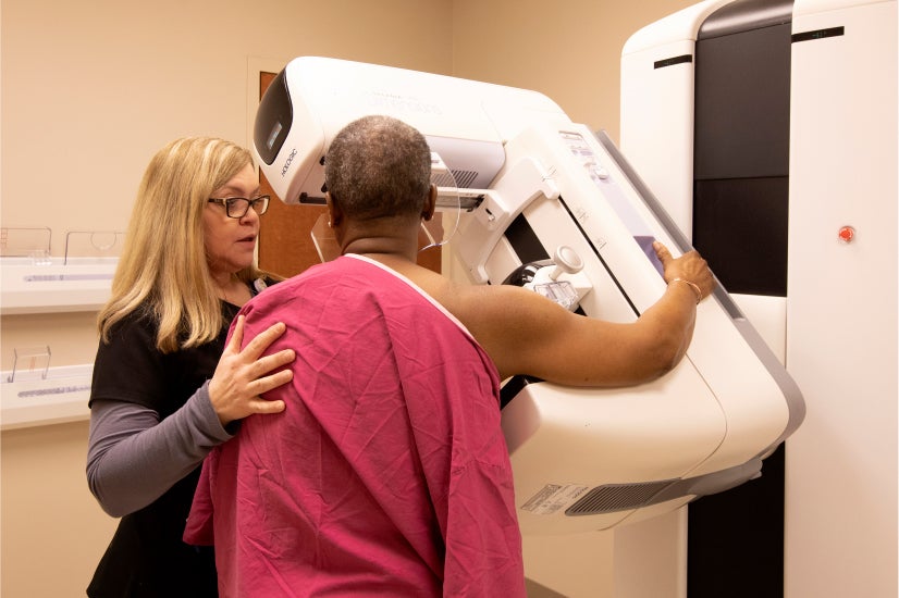 Clinician conducting a 3-D mammogram on a female patient. Clinician conducting a 3-D mammogram on a female patient.
