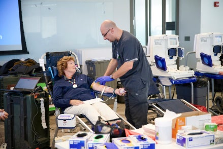 Man helps female Medline employee donate blood. Man helps female Medline employee donate blood.
