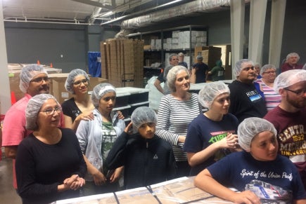 People wearing hair nets stand next to boxes. People wearing hair nets stand next to boxes.