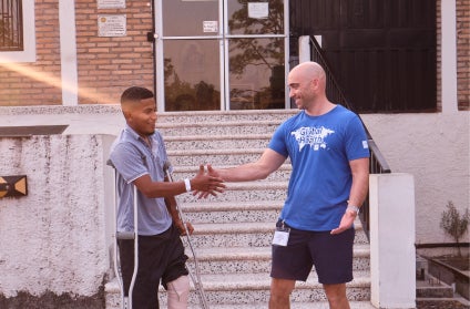 A Medline employee and Honduran patient shake hands in front of a healthcare facility. A Medline employee and Honduran patient shake hands in front of a healthcare facility.