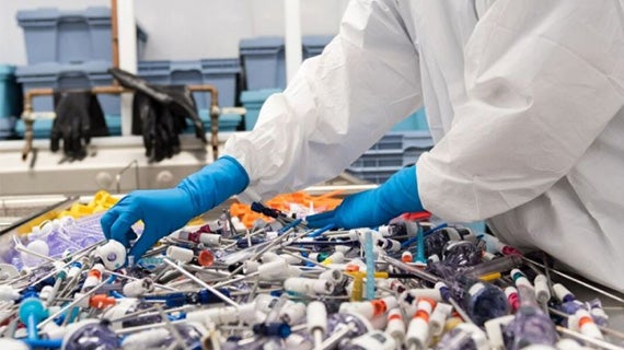 Worker wearing gloves sorts through medical devices. Worker wearing gloves sorts through medical devices.