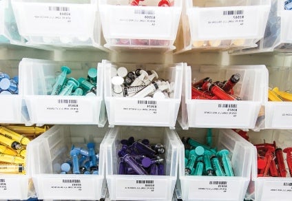 Image depicting Riverside Healthcare’s improve care quality case study White bins with various colored syringes in each bin
