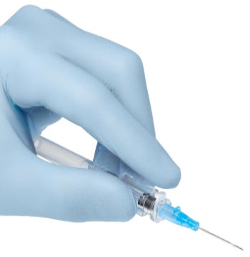 Gloved caregiver’s hands holding a safety catheter Gloved caregiver's hands holding a safety catheter