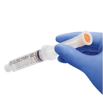 Gloved clinician’s hand holding pre-filled saline flush syringe to reveal orange cap used to close the line after it is flushed Gloved clinician's hand holding pre-filled saline flush syringe to reveal orange cap used to close the line after it is flushed
