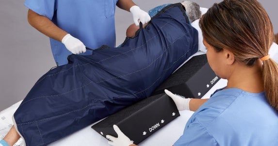 PAP_CGLIDESHEETNS_AD with Models_042_RGB 1-min Caregivers moving patient with repositioning sheet, while sliding ComfortGlide wedges under them