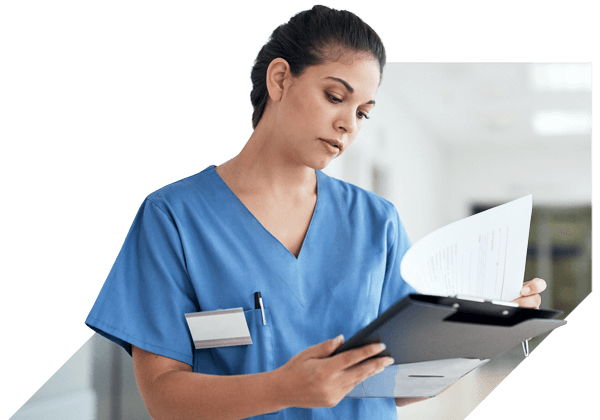 Clinician in blue scrubs wearing a stethoscope, looking at papers on a clipboard Clinician in blue scrubs wearing a stethoscope, looking at papers on a clipboard