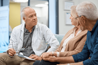 Health-literacy Doctor in white coat consulting with a male and female patient who are holding hands
