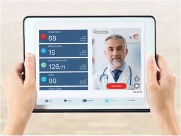 transition-3-min Close-up of hands holding a tablet while doctor on screen goes over patient vital signs during a telehealth appointment