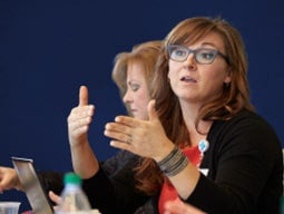 Brown-haired caucasian woman talking and gesturing with her hands Illustration of a computer with bar graph on the screen representing customized product data reporting