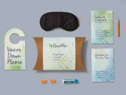 Neatly arranged contents of QuietPac kit with ear plugs, “voices down please” door sign, eye mask and puzzle booklet Illustration of tiny grey ones and zeroes with three big blue bars in a blue magnifying glass