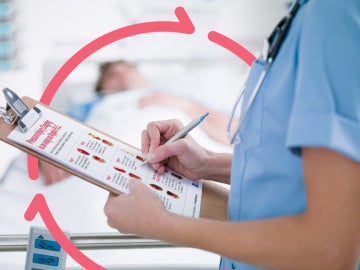 refocus Clinician holding clipboard at foot of patient bed