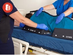 Nurse and EMS worker placing ComfortGlide sheet on gurney mattress Nurse and EMS worker placing ComfortGlide sheet on gurney mattress